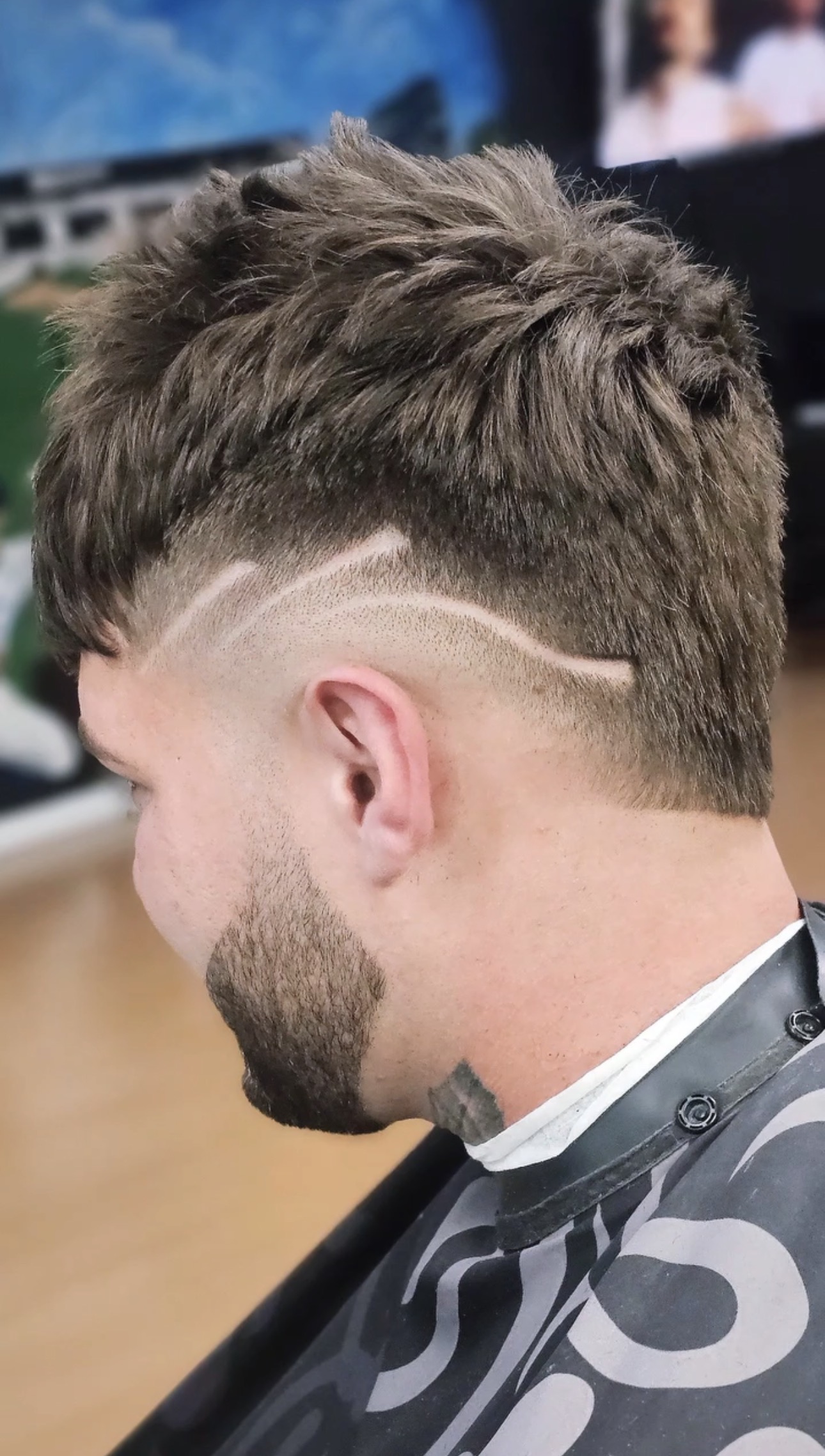 Textured crop with a curved line design shaved into the fade