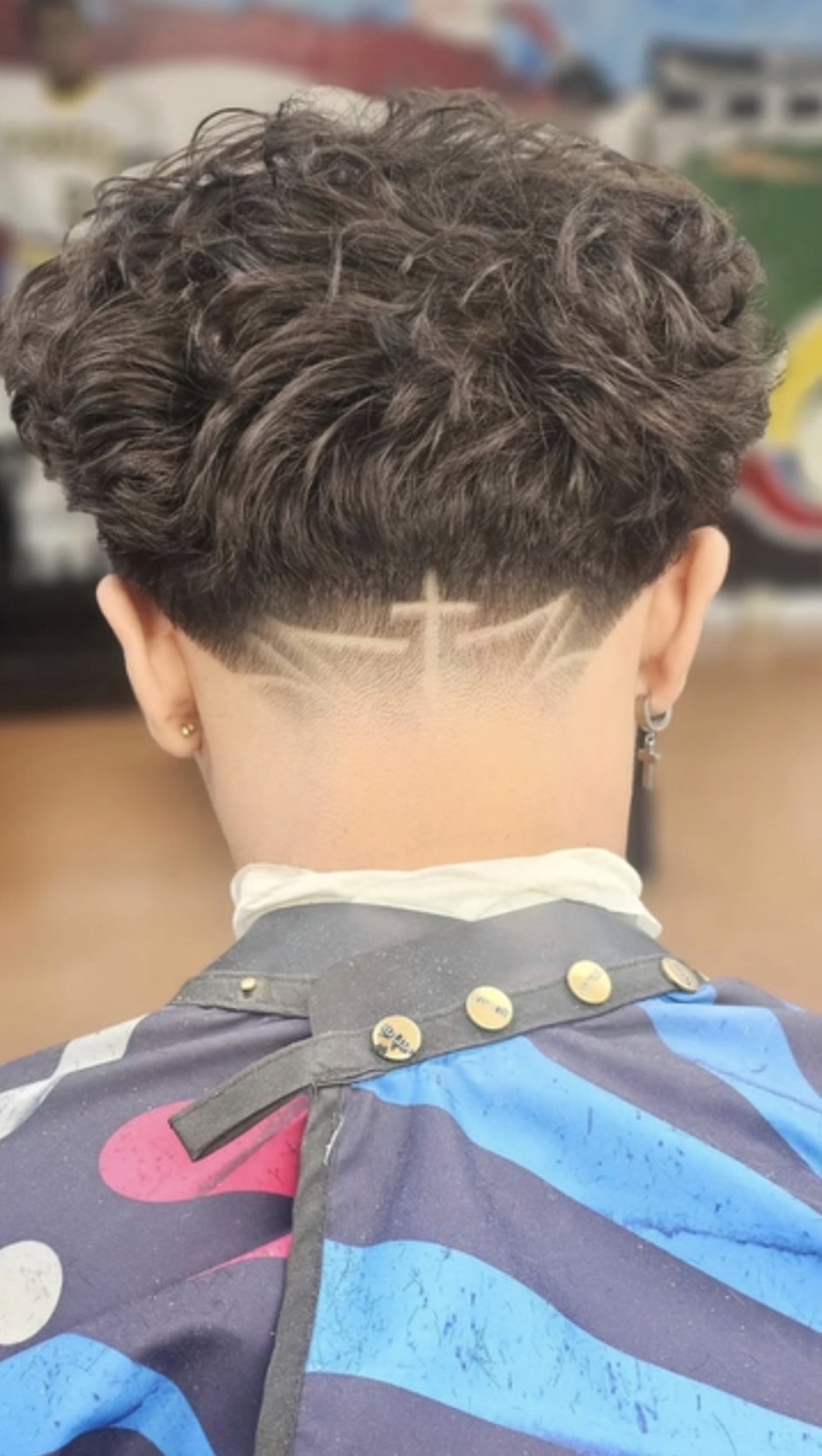 Cross design shaved into a curly taper at the nape